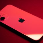 Close-up of a red smartphone with dual lenses on a red backdrop, highlighting sleek design and technology.